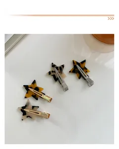 Close-up of four star-shaped tortoiseshell acetate hair clips with metal duckbill base