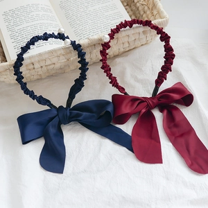 Détail de serre-têtes en tissu bleu marine et bordeaux avec perles et nœuds en satin