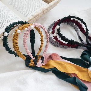 Détails des accents de perles et longs rubans de soie sur bandeaux en tissu coloré