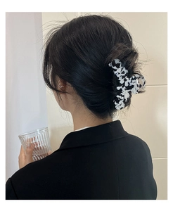 Vue détaillée d'une grande pince à cheveux motif vache noir et blanc sur une coiffure relevée