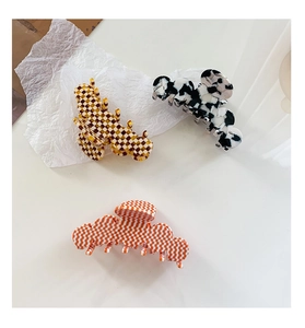 Détails de pinces à cheveux colorées à motif damier et vache sur fond blanc pur
