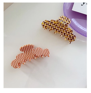 Vue de dessus de pinces à cheveux à damier orange et marron sur surface blanche