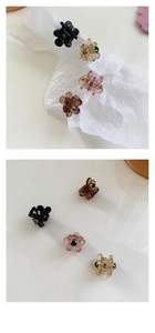Dettaglio di piccole mollette per capelli a camelia con strass verdi in vari colori