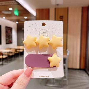 Détail de pinces à cheveux étoiles jaunes mates et barrette ovale violette