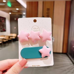 Détail de barrettes étoiles roses en résine mate sur une base ovale vert foncé