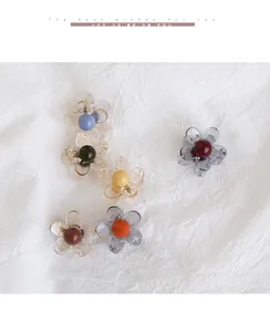 Dettaglio di piccoli fermagli per capelli a forma di camelia in colori assortiti e metallo