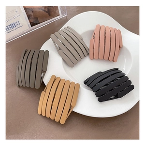 Close-up of five matte bird nest hair clips in assorted colors on a ceramic tray