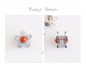 Dettaglio di un mini fermaglio per capelli a forma di camelia con petali grigi e perla arancio