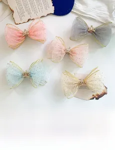 Detail of five mesh bow hair clips with gold crown accents and glittering organza fabric