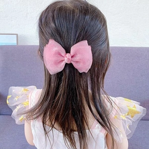 Detailed back view of a pink mesh bow hair clip worn by a girl on long hair