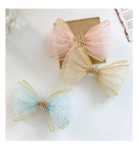 Close-up of children mesh bow hair clips with gold sequins and small crown details