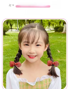 Sweet red mesh bow hair clip on girl's braids in a sunny outdoor garden setting
