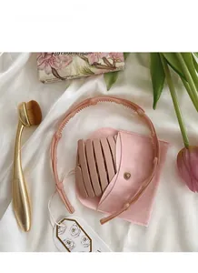 Close-up of foldable pink headband with non-slip teeth and matching velvet storage bag