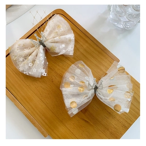 Detail of mesh bow hair clips with gold sequins and rhinestone crown embellishments