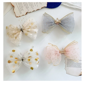Detailed close-up of four mesh bow hair clips with rhinestone crown accents and gold dots