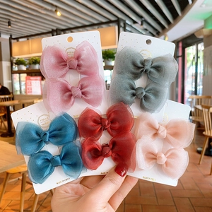 Detail of handmade mesh bow hair clips in five colors on white display cards