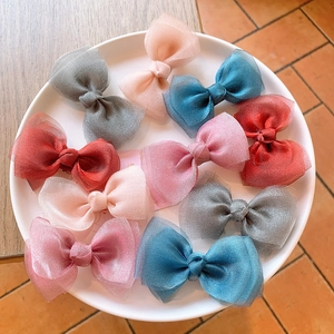 Detailed close-up of colorful organza bow hair clips with layered mesh texture in a tray