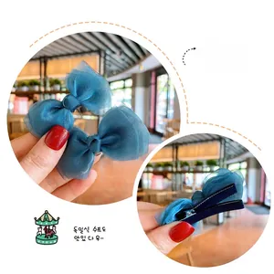 Detail of blue mesh bow hair clips showing front fabric and rear metal duckbill clip