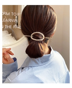 Detail view of a pearl hair clip set styled in a low bun with a gold pin and ring