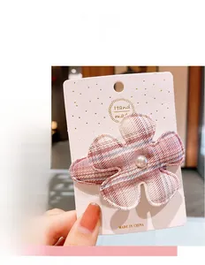 Détail d'une barrette fleur à carreaux roses avec perle blanche sur carte support