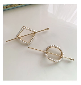 Detail view of gold alloy hair pins set with elegant round white pearls in geometric shapes