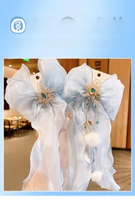 Détail de pinces à cheveux noeud en organza bleu clair avec strass flocon et pompons doux