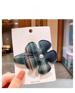 Détail d'une pince à cheveux fleur à carreaux avec perle sur carte blanche