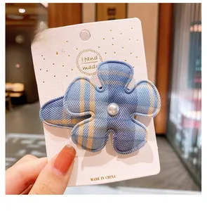 Détail d'une pince à cheveux fleur à carreaux bleu et jaune avec perle centrale