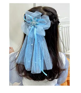 Détail d'une pince à cheveux avec nœud en tulle bleu, flocons et rubans élégants