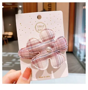 Gros plan d'une pince à cheveux fleur à carreaux rose avec perle sur carton