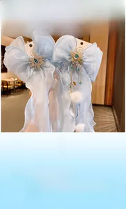 Détail de la pince à cheveux noeud en tulle bleu clair avec émeraude, pompon et chaîne