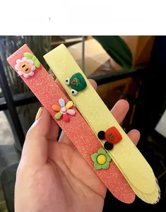 Close-up of pink and yellow glitter fringe hair clips with cute 3D cartoon ornaments