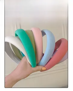Group of colorful sponge headbands in cream tones held by hand for a close-up detail view