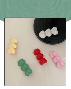 Detail of colorful acrylic heart hair clips in cream, green and red on elegant display
