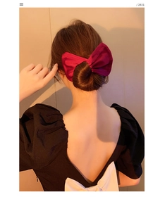 Detailed back view of a deep red satin bow hair clip styled on an elegant low bun