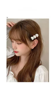 Close-up of a white flower hair clip and classic double C earrings on a female model