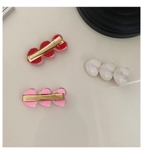 Close-up of three colorful heart-shaped hair clips with gold metal bases for girls