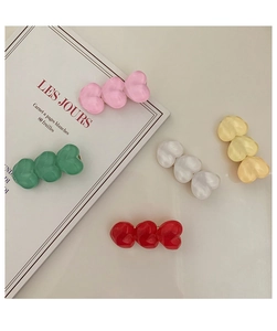 Detail view of five colorful heart-shaped resin hair clips on a soft cream background