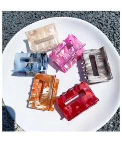 Flat lay of rectangular acetate hair claws with marble textures in six assorted colors