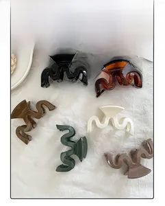 Macro detail of wave-shaped acetic acid hair claws in six varied colors on white cloth