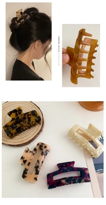 Macro detail of various floral patterned acetate hair claws on a minimalist wooden display