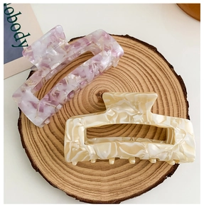 Macro view of large square acetate hair claws with floral and marble textures