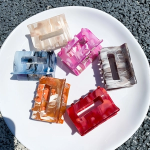 Rectangle acetate hair claw clip set in six marble patterns displayed on a white plate
