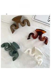 Macro view of four wave-shaped resin hair claws in tortoiseshell and neutral colors