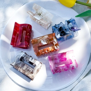 Medium acetate hair claws in marble and tortoiseshell patterns displayed on a white plate