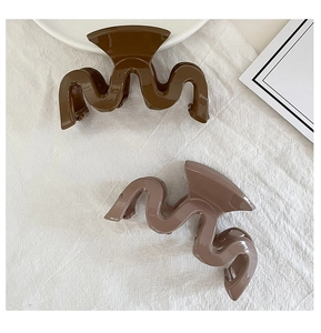 Macro detail of large S-shaped wavy hair claws in coffee and nude pink acrylic