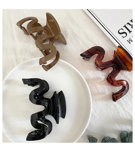 Detail view of large wave-shaped hair claws in dark brown, amber and glossy black