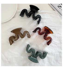 Detail view of wave-shaped hair clips in black, brown, amber, and dark green colors
