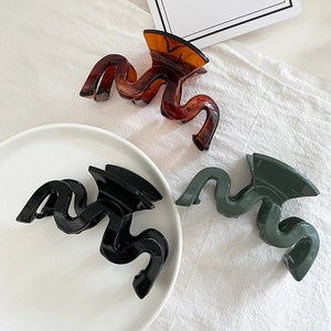 Three-piece set of large wavy geometric hair claws in amber, black, and forest green