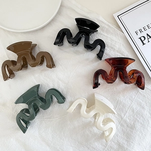 Set of five wavy geometric hair claw clips in glossy black, amber, and cream colors